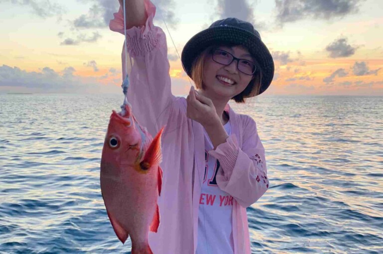 旅客在夕陽海面展示夜釣成果